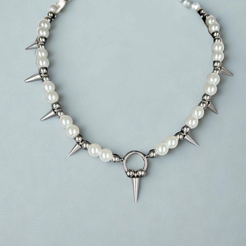 Gothic punk choker with metal spikes and imitation pearls on flat surface