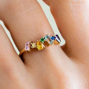 Hand wearing gold ring with multicolor zircon stones, stylish and elegant