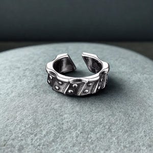 May include: A white ceramic mug with a black handle and the text "But First, Coffee" in a black, bold font. The mug is sitting on a wooden surface. The mug is approximately 4 inches tall.