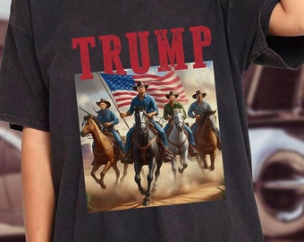 May include: Black t-shirt with a graphic of four cowboys riding horses with an American flag. The text "TRUMP" is printed above the graphic.