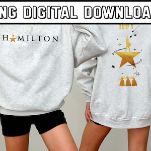 May include: Light gray sweatshirt with "HAMILTON" printed on the front and a gold star. The back features a gold star with a silhouette and the text "2022". The top is a digital download.