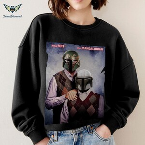 May include: Black sweatshirt with a graphic print of Boba Fett and The Mandalorian characters from Star Wars. The text "Boba Fett" and "The Mandalorian" are printed on the graphic.