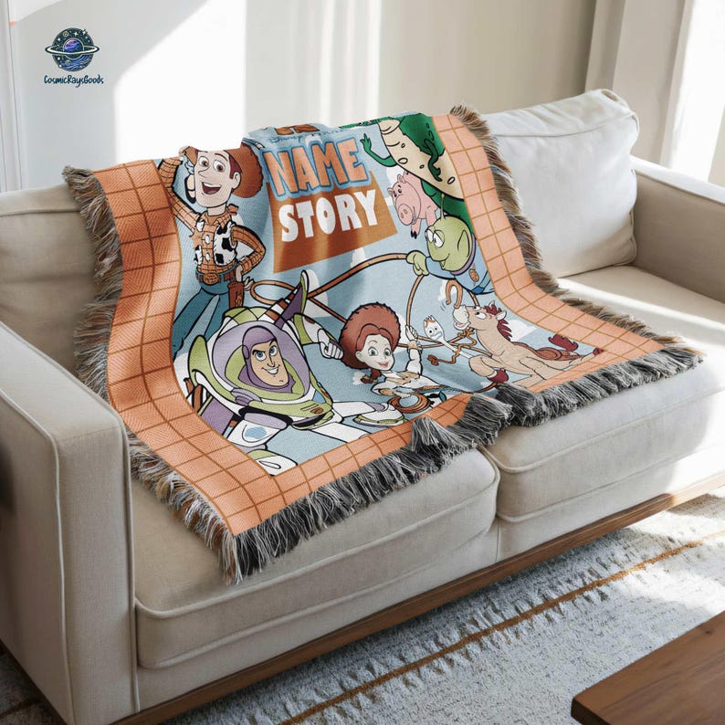 A colorful, cartoon-style blanket with characters from the Toy Story movie, including Woody, Buzz Lightyear, and other beloved characters, is draped over a white couch.