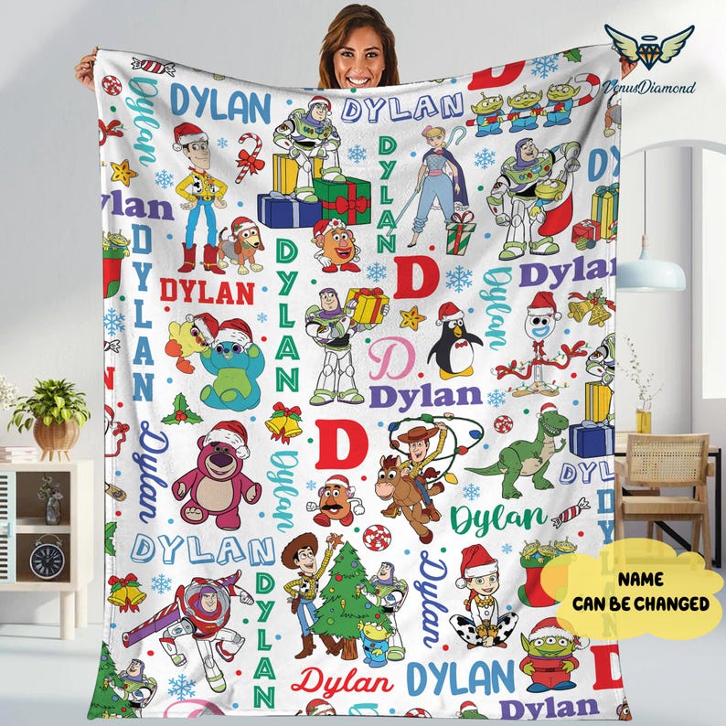 May include: A white fleece blanket featuring various Toy Story characters in festive holiday attire. The blanket is decorated with the name "Dylan" and Christmas-themed elements like snowflakes and presents. The name can be changed.