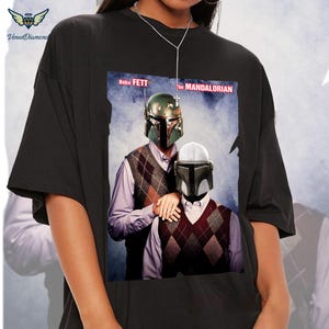 May include: Black t-shirt with a graphic of Boba Fett and The Mandalorian in a casual setting. The text "Boba Fett" and "The Mandalorian" are printed on the shirt.