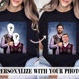 May include: A black t-shirt featuring a personalised photo of two people wearing jumpers. The photo is set against a blue and white background. The text "PERSONALIZE WITH YOUR PHOTO" is at the bottom of the image.