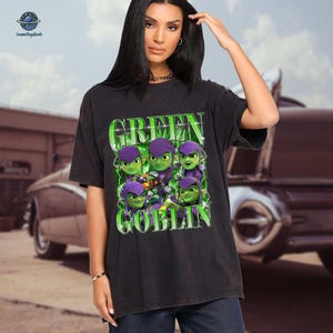 A woman wearing a black t-shirt with a graphic design featuring green and purple characters resembling the Green Goblin from the Spider-Man movies.