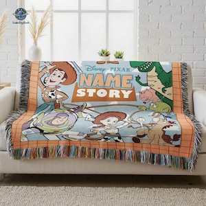 A Disney Pixar-themed blanket with characters from the Toy Story movie, including Woody, Buzz Lightyear, and other beloved characters, is displayed on a couch.