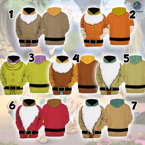 Pode incluir: Sete camisolas com capuz apresentando estampas gráficas de trajes de anões com barbas brancas, cintos pretos e fivelas douradas. Cada camisola exibe um esquema de cores único, incluindo bege, laranja, verde-limão, castanho, vermelho e areia.