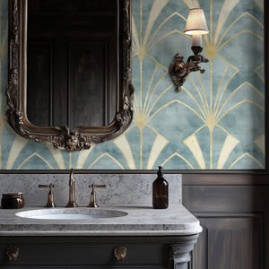 Puede incluir: Un baño con una estética vintage. El tocador tiene una encimera de mármol y un mueble gris oscuro. La pared presenta un papel pintado art déco azul y dorado. Un espejo y una lámpara de pared con marco de bronce completan el look.