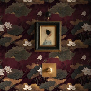 Könnte beinhalten: Ein gerahmtes Porträt einer Frau in einem blauen Kleid hängt an einer Wand mit einem bordeauxfarbenen Blumenmuster. Das Muster zeigt Lotusblumen und Blätter in Braun-, Grün- und Weißtönen. Ein Lichtschalter aus Messing und ein dekorativer Wandhaken sind ebenfalls sichtbar.