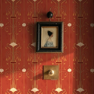 Peut inclure: Un mur rouge avec un motif floral doré et blanc répété. Un petit portrait encadré d'une femme en robe bleue est accroché au mur, ainsi qu'un bouton de porte en laiton et un crochet noir.