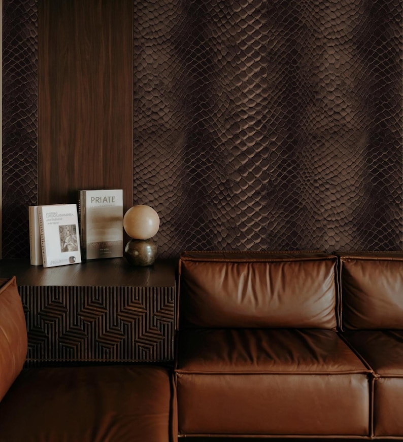 May include: A living room scene featuring a brown leather sofa, a dark wood side table with books and a decorative sphere, and a wall with a snakeskin pattern. The color palette is dominated by shades of brown and dark wood.