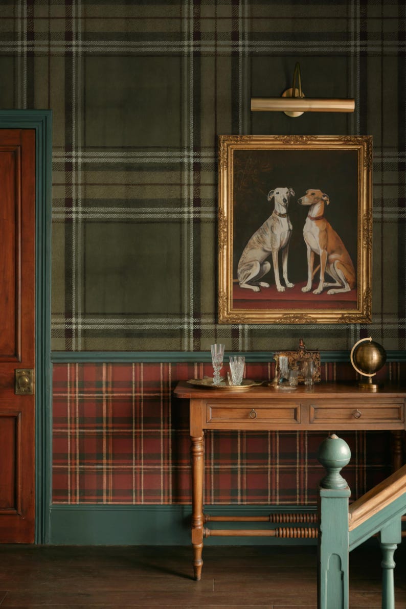 May include: A room featuring a framed painting of two dogs, set against a backdrop of plaid wallpaper in green, red, and brown. A wooden table with decorative items sits below the artwork, enhancing the room's classic aesthetic.