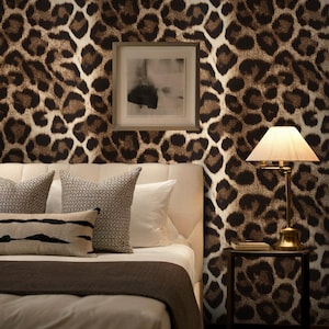 May include: A bedroom featuring leopard print wallpaper. The bed has white bedding and decorative pillows. A small side table with a lamp is beside the bed. A framed abstract art piece hangs on the wall.