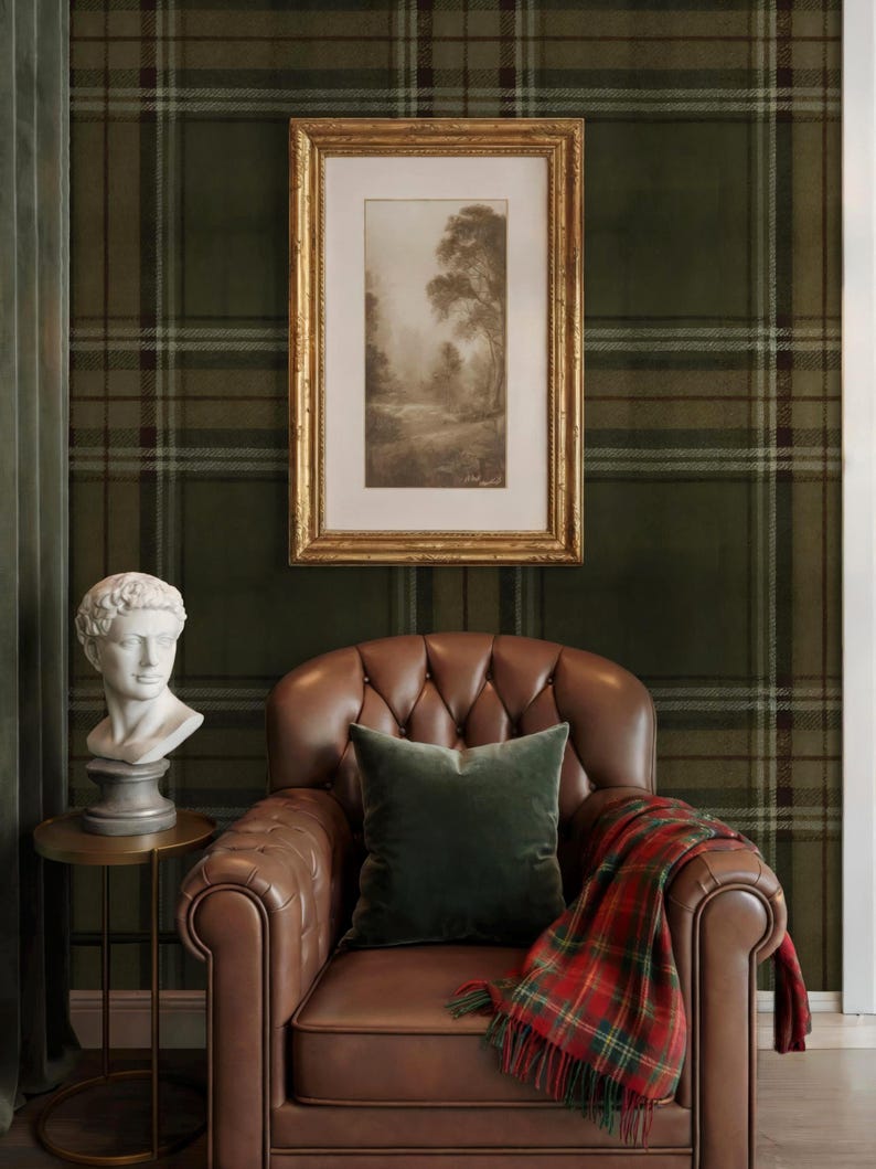 May include: An interior scene with a brown leather armchair, a green velvet cushion, and a red tartan blanket. A framed landscape print hangs above the chair. A white bust sits on a small gold side table, against a green plaid wallpaper.