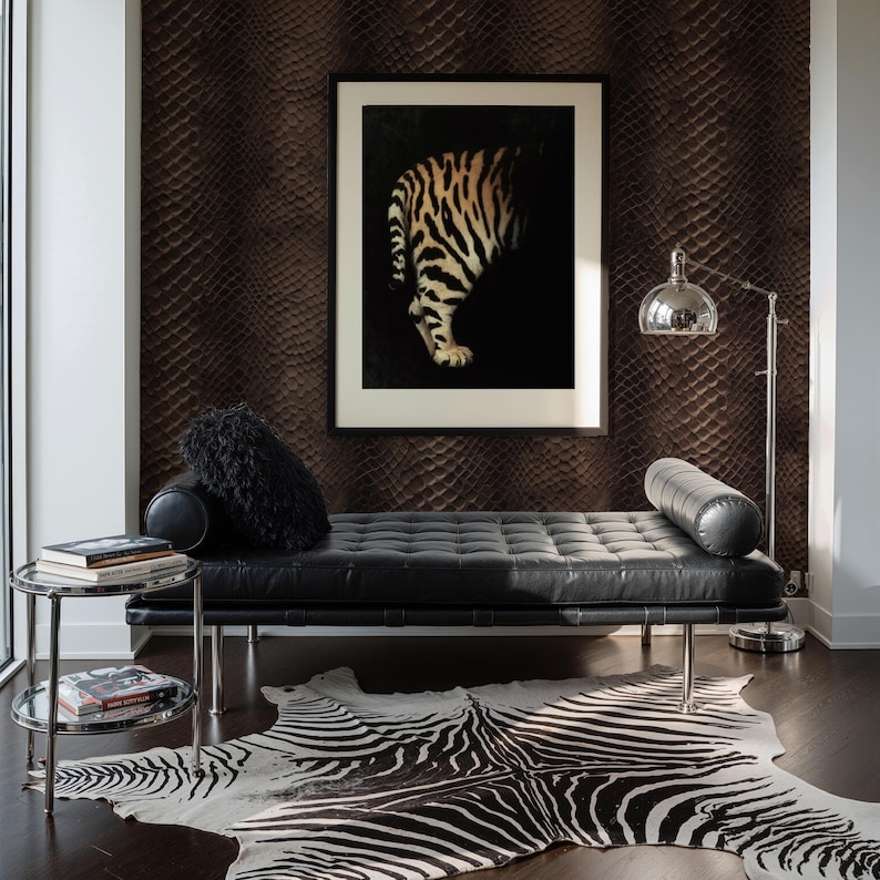 May include: A modern living room featuring a black leather chaise lounge, a zebra-print rug, and a framed artwork of a tiger. A chrome side table holds books, and a silver floor lamp provides light. The wall has a textured, dark brown pattern.
