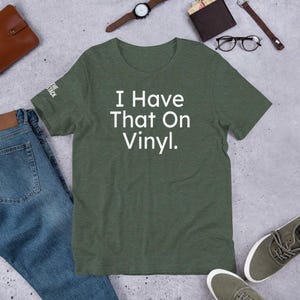 Può includere: Una maglietta verde con la scritta "I Have That On Vinyl." stampata in bianco.