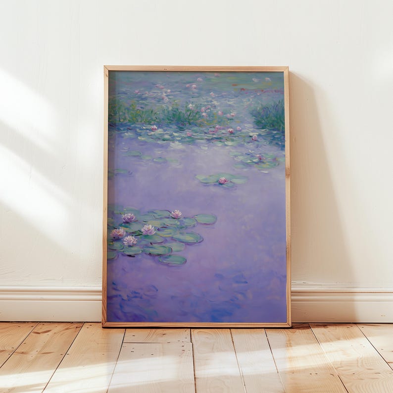 Op de afbeelding: Een ingelijste print van een waterlelievijver. Het kunstwerk heeft een zachte, impressionistische stijl met tinten paars, groen en roze. Waterlelies en bloemen drijven op het wateroppervlak, wat een serene sc&egrave;ne cre&euml;ert.