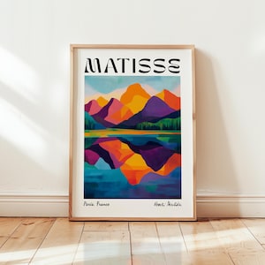 Könnte beinhalten: Ein gerahmter Kunstdruck mit einer farbenfrohen Berglandschaft, die sich in einem See spiegelt. Das Kunstwerk mit der Aufschrift "MATISSE" zeigt leuchtende Farben wie Orange, Lila und Blau. Der Druck enthält den Text "Paris, France" und "Henri Matisse."