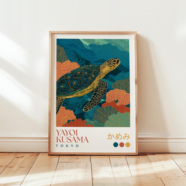 Framed Yayoi Kusama-inspired art print propped against a white wall on a wooden floor. The artwork features a sea turtle swimming through a colorful coral reef in shades of teal, orange, and gold, with stylized dot textures and flowing patterns. Japanese text and a colour palette are printed below the image.