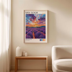 Framed Van Gogh-inspired lavender field print mounted above a wooden bench with white vases. Thick impasto brushwork shows a vivid sunset with purples, oranges, and blues. Bold "VAN GOGH" text and palette swatches sit below. Set against a beige wall with soft daylight for a clean, minimal look.