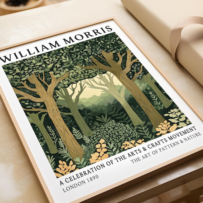 Close-up of a William Morris forest scene art print in a natural wood frame, lying flat on a table beside brown paper wrapping. The illustration highlights the intricate leaf patterns, textured tree trunks, and golden flower details at the forest edge, with misty green hills and a pale yellow sky in the background. Bold black text frames the design, honouring the Arts & Crafts Movement and its dedication to the beauty of nature.