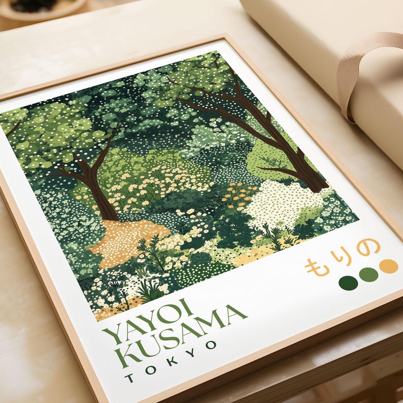 Close-up of framed Yayoi Kusama-inspired forest art print featuring dotted green trees and foliage in layered shades, with Japanese text and earthy color swatches, placed on a table beside wrapping paper for packaging