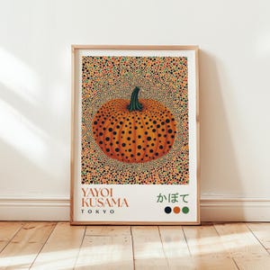 May include: Framed art print featuring an orange pumpkin with black spots, set against a background of colorful dots. The print includes the text "YAYOI KUSAMA TOKYO" and Japanese characters. The artwork is displayed in a wooden frame.