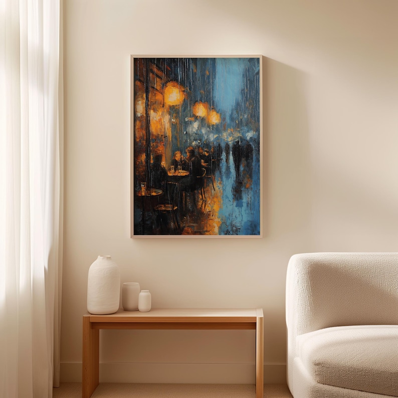 Monet art poster above a minimalist wooden bench with small white vases in a calm, neutral setting. The painting shows a rainy evening café, glowing with amber light that spills onto the wet pavement. Figures are rendered in shadowy blues and blacks, blurred by rain and brushwork, with vibrant orange reflections dancing across the street. The impressionist style emphasizes texture and mood, framed in natural wood.