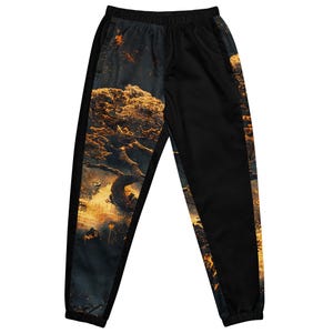 May include: Black track pants with a striking design. One side features a detailed, golden-toned tree illustration against a dark background. The other side is solid black, with a black stripe down the side. The pants have an elastic waistband.