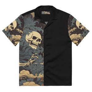 May include: Black short-sleeved button-down shirt with a unique design. One side features a skull and floral pattern in beige, blue, and brown, while the other side is solid black. The shirt has a classic collar and a tag with text.