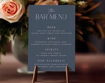 May include: A rectangular dark blue bar menu sign with white text reading The Bar Menu, Beer, Wine, Spirits, and Non-Alcoholic, listing various drink types. The sign is held upright by a small, simple wooden stand with two thin, angled legs.