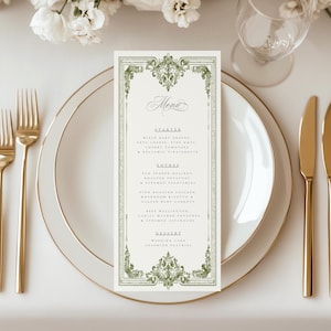 Könnte beinhalten: Eine cremefarbene Menükarte mit einem dekorativen grünen Rand und dem Wort "Menu" in eleganter Schrift. Das Menü listet Vorspeisen, Hauptgerichte und Desserts auf. Die Karte liegt auf einem weißen Teller mit goldenem Besteck, passend für eine Hochzeit oder ein formelles Abendessen.