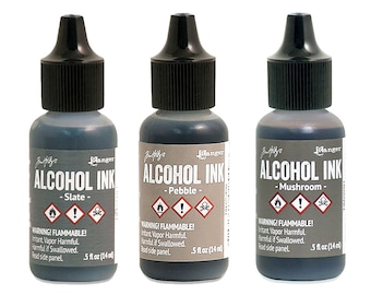 Könnte beinhalten: Drei Flaschen Ranger Alcohol Ink in den Farben Schiefer, Kiesel und Pilz. Jede Flasche hat einen schwarzen Deckel und ein Etikett mit Warnhinweisen und dem Namen der Tinte. Jede Flasche enthält 14 ml Tinte.