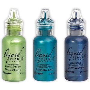 May include: Three bottles of Liquid Pearls dimensional pearlescent paint in Succulent, Bahama Bay, and Deep Water colors. Each bottle has a clear cap and contains 0.5 fl oz / 15 ml of paint. The bottles are labeled with the brand name and color.