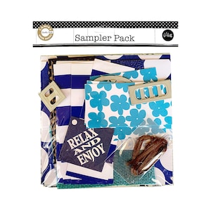 May include: A sampler pack of paper crafting supplies featuring blue and white striped paper, blue and white floral patterned paper, a turquoise blue fabric, a brown ribbon, and a tag that says "Relax and Enjoy".