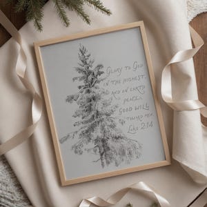 May include: A framed print with a pencil sketch of a snow-covered evergreen tree. The artwork is in a light wood frame and features the text "Glory to God in the Highest, and on Earth peace, good will toward men. Luke 2:14."