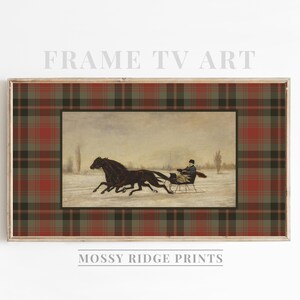 K&ouml;nnte beinhalten: Gerahmter Druck mit einer Winterszene, in der zwei schwarze Pferde einen Schlitten durch den Schnee ziehen. Das Kunstwerk ist von einem rot-gr&uuml;n-braunen Karomuster umgeben. Der Text "FRAME TV ART" und "MOSSY RIDGE PRINTS" sind sichtbar.
