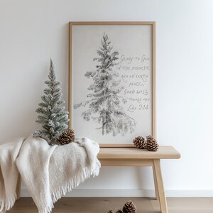 May include: A pencil sketch of a Christmas tree in a wooden frame with the text "Glory to God in the Highest, and on Earth peace, good will toward men, Luke 2:14." A small, snow-covered artificial tree and pine cones sit on a wooden bench with a cream-coloured throw.