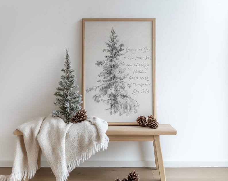 May include: A pencil sketch of a Christmas tree in a wooden frame with the text "Glory to God in the Highest, and on Earth peace, good will toward men, Luke 2:14." A small, snow-covered artificial tree and pine cones sit on a wooden bench with a cream-coloured throw.
