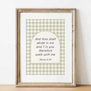 Op de afbeelding: Ingelijste print met een lichtbruine houten lijst. De print heeft een lichtgroene en witte gingham patroon achtergrond. De tekst "And thou shalt abide in me, and I in you: therefore walk with me. Moses 6:34" wordt weergegeven in een crèmekleurige boog.