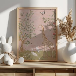 May include: A framed art print featuring a giraffe, birds, and butterflies in a whimsical garden scene. The artwork has a soft pink background with trees bearing fruit. The frame is a light wood color.