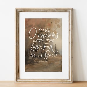 May include: Framed art print with a neutral color palette. The artwork features the text "O Give Thanks Unto The Lord; For He Is Good" in white script. The frame is a light brown color.