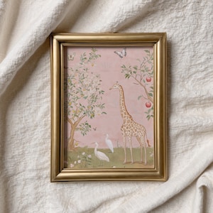 May include: A framed print featuring a giraffe, two white birds, and butterflies in a whimsical garden scene. The artwork has a pink background with trees bearing fruit and flowers. The frame is gold.