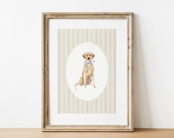May include: A framed watercolour print featuring a yellow Labrador Retriever wearing a blue bow. The dog is set in an oval against a cream background with a vertical blue floral pattern. The frame is light brown.