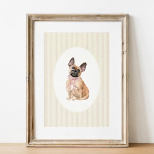 May include: A framed watercolour painting of a French Bulldog wearing a pink bow. The dog is depicted in a seated position, with a light brown coat and black ears. The background is a cream-coloured wallpaper with vertical stripes and floral patterns, in a wooden frame.