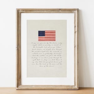 Puede incluir: Impresión enmarcada con la bandera estadounidense con rayas rojas y blancas y un campo azul de estrellas. La impresión incluye un poema en escritura cursiva. El marco es de color marrón claro.