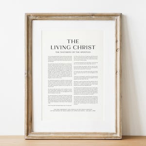 May include: Framed print with the text "THE LIVING CHRIST THE TESTIMONY OF THE APOSTLES" in black font. The print is in a light-colored wooden frame. The print is on a white background.