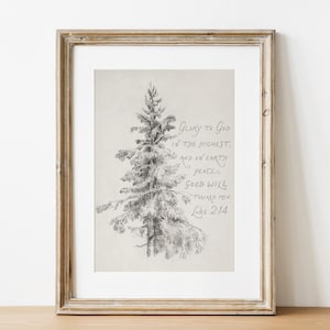 May include: A framed print with a pencil sketch of a fir tree. The artwork includes handwritten text with the words "Glory to God in the highest, and on earth peace, good will toward men, Luke 2:14". The frame is a light brown colour.